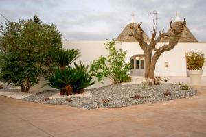 a garden in front of a building with trees at Pavì Trulli e Suites in Locorotondo