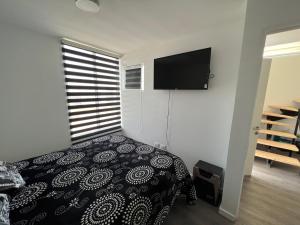 een slaapkamer met een bed en een flatscreen-tv bij Casa Playa el Tabo en Condominio Estilo Mediterraneo in El Tabo