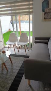 sala de estar con 2 sillas blancas y sofá en Casa Playa el Tabo en Condominio Estilo Mediterraneo en El Tabo