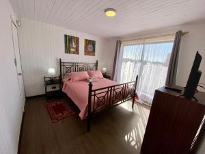 a bedroom with a bed with pink sheets and a window at Hostal Dolegant Pichilemu 2 in Pichilemu