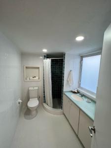 a bathroom with a toilet and a sink and a window at OceanBlue Resort in Christ Church