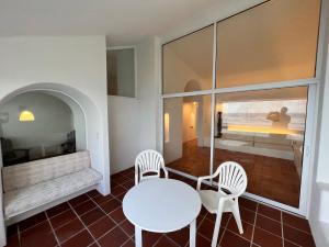 a white table and chairs in a room with a window at OceanBlue Resort in Christ Church