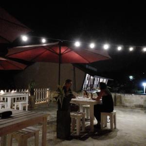 two people sitting at a table under an umbrella at night at Ocean Breeze Villa in Matara
