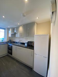 a kitchen with white appliances and a white refrigerator at Lovely 1-bedroom apartment with garden and parking in Stone