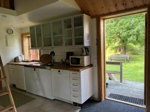 una cocina con microondas y una puerta a un patio en Highnoon Westernranch guesthouse en Ljusdal