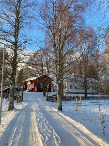 a snow covered road in front of a red barn at Highnoon Westernranch guesthouse in Ljusdal