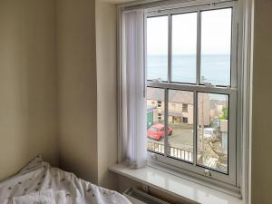 a bedroom with a window with a view of the ocean at Frannys Cottage in Penmaen-mawr
