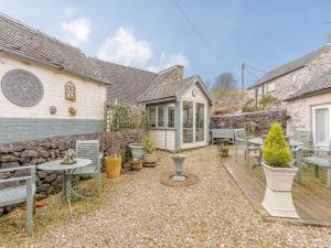 a backyard with a table and chairs and a stone wall at The Smithy - E5445 in Brassington