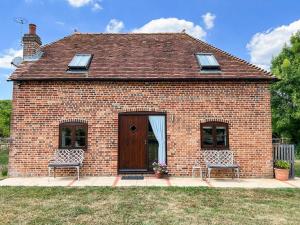 a brick house with two chairs and a wooden door at The Lodge in Thakeham