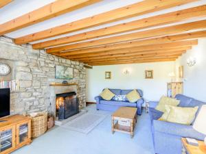 a living room with a stone fireplace and blue couches at Town Head Cottage in Carlton