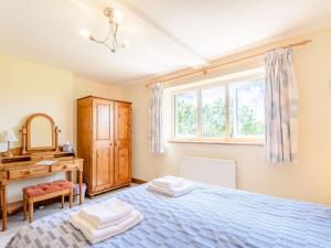 a bedroom with a bed and a desk and a window at Town Head Cottage in Carlton