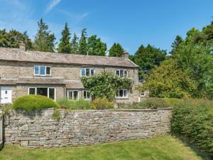 an old stone house with a stone wall at Town Head Cottage in Carlton