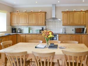 una cocina con una mesa de madera con un jarrón de flores. en The Mill House, en Warenford