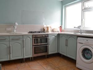 a kitchen with a stove and a washing machine at Seagulls in Holyhead