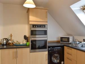 a kitchen with a stove and a microwave at Kimberley Apartment in Alness