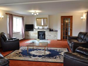 a living room with leather furniture and a fireplace at Copper Beech in Netherbury