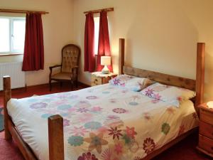a bedroom with a bed with a floral bedspread at Copper Beech in Netherbury