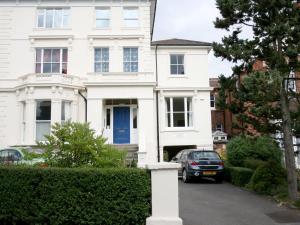 een wit huis met een blauwe deur en een auto bij Hamilton House in Royal Tunbridge Wells