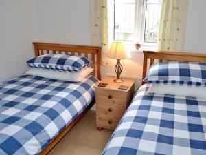 a bedroom with two beds and a lamp on a night stand at Meadowside Apartment in Fowey