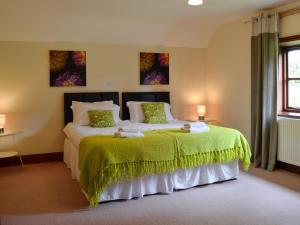 a bedroom with a large bed with a green blanket at Brynich Villa in Brecon
