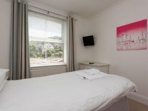 a bedroom with a white bed and a window at Evelyn Cottage in Dartmouth