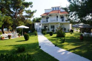 een wit huis met een tuin en een loopbrug bij Villa Iris in Prinos