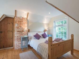a bedroom with a bed and a brick wall at The Coach House Stables in Graveney