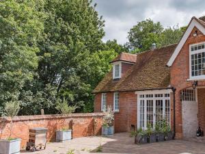 a brick house with a brick wall and trees at The Coach House Stables in Graveney