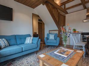 The Coach House Stables في Graveney: غرفة معيشة مع أريكة زرقاء وطاولة