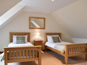 two beds in a attic bedroom with a mirror at Hawthorn House in Tomintoul