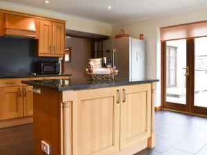 a kitchen with wooden cabinets and a black counter top at Hawthorn House in Tomintoul