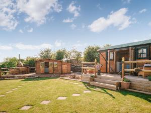 un gran patio con una cabaña y una casa en Nirvana, en Stoodleigh