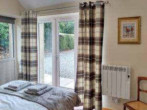 a bedroom with a bed in front of a window at The Smiddy in Glasserton