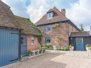 an old brick house with a blue garage at Woolhouse Barn in Hunton