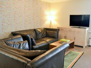 a living room with a leather couch and a television at The Maltings in Bamburgh
