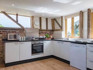 a kitchen with white cabinets and a brick wall at Norwood Barn in Maidstone