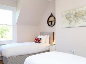 two beds in a white room with a map on the wall at Skyfall in Canterbury