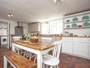 a kitchen with a table with a cake on it at The Old Farmhouse in Chardstock