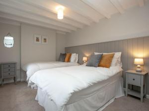 a bedroom with two beds with white sheets and lamps at The Old Farmhouse in Chardstock