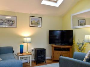 sala de estar con TV de pantalla plana y chimenea en The Annexe en Barham
