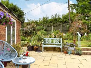 a garden with a white bench and some plants at The Annexe in Barham