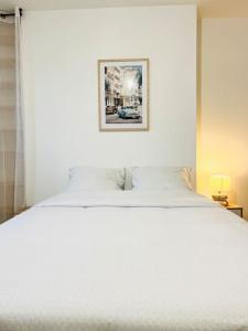 a white bed with a picture hanging above it at M.A.H 2 Le calme en hyper centre magnifique in Le Havre