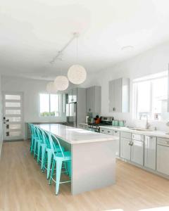 a kitchen with white cabinets and blue bar stools at Coconut Breeze 2 in Saint Philip