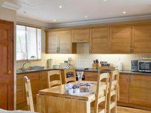 una cocina con armarios de madera y una mesa y sillas de madera. en Waren View, en Warenford
