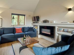a living room with blue couches and a fireplace at Station Lodge in Stretton on Fosse