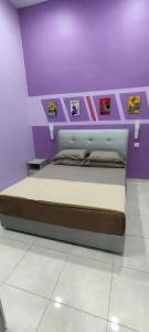 AMMAR FATIMAH HOMESTAY @ MERLIMAU, MELAKA في Merlimau: غرفة نوم بسرير في غرفة ارجوانية