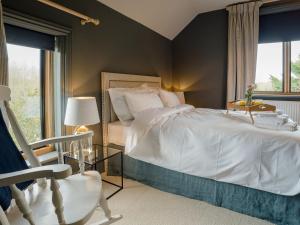 a bedroom with a white bed and a chair at Station Lodge in Stretton on Fosse