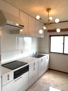 cocina con armarios blancos, fregadero y ventilador de techo en ガナダン中央駅 3f 無料駐車場, en Kagoshima