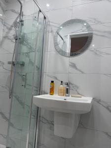 La salle de bains blanche est pourvue d'un lavabo et d'un miroir. dans l'établissement Belvue Serviced Apartment - Ealing Broadway, à Ealing