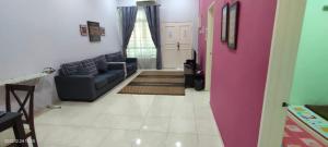 AMMAR FATIMAH HOMESTAY @ MERLIMAU, MELAKA في Merlimau: غرفة معيشة مع أريكة وباب وردي